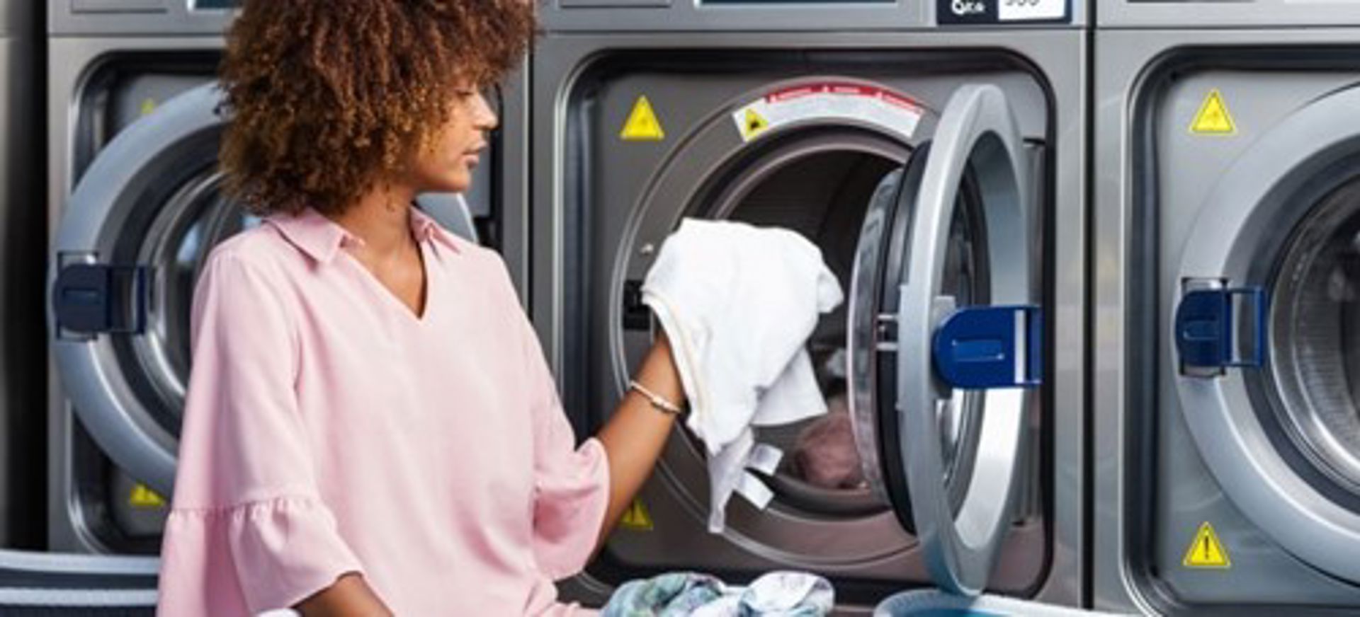 Woman Loading Washing Machine At Laundromat Min